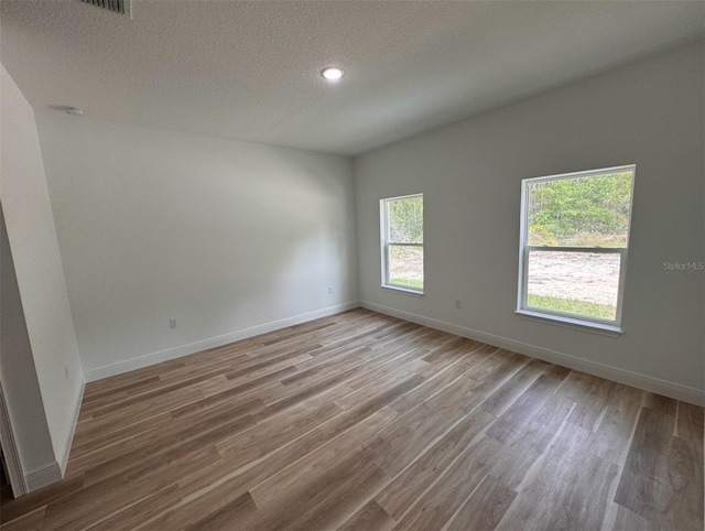 empty room with a textured ceiling and wood-type flooring