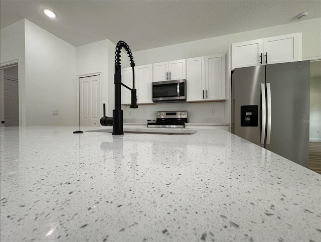 kitchen featuring light stone countertops, white cabinets, and stainless steel appliances