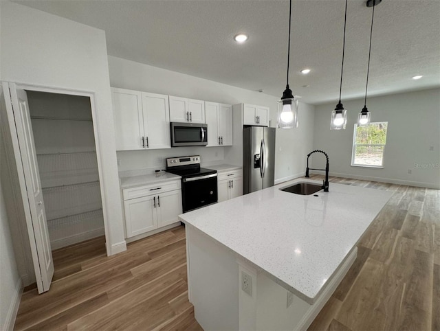 kitchen with appliances with stainless steel finishes, hanging light fixtures, white cabinets, and wood-type flooring