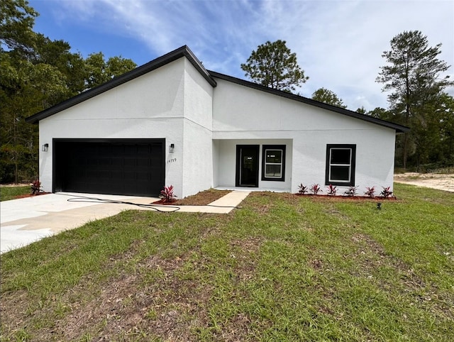 view of front facade with stucco siding, an attached garage, concrete driveway, and a front yard