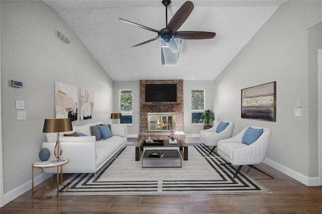 living room featuring ceiling fan, a fireplace, a textured ceiling, dark hardwood / wood-style flooring, and brick wall