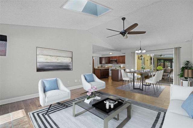 living room with lofted ceiling with skylight, ceiling fan with notable chandelier, dark hardwood / wood-style floors, and a textured ceiling