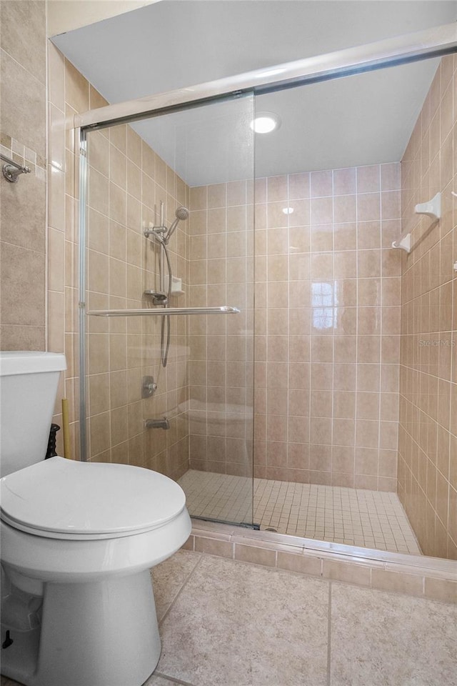 bathroom featuring tile flooring, an enclosed shower, and toilet