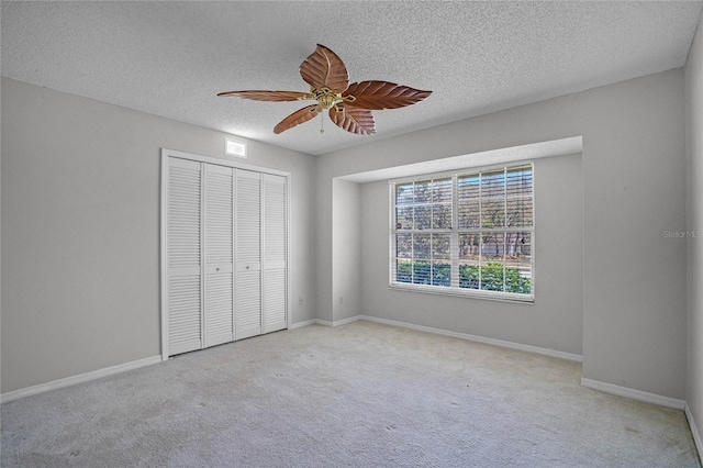 unfurnished bedroom featuring light colored carpet, a closet, ceiling fan, and a textured ceiling