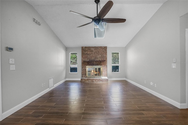 unfurnished living room featuring a brick fireplace, ceiling fan, brick wall, lofted ceiling, and a textured ceiling