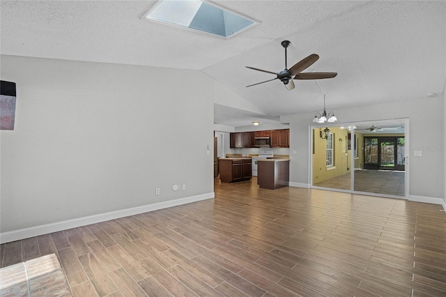 unfurnished living room featuring high vaulted ceiling, ceiling fan with notable chandelier, a textured ceiling, wood-type flooring, and a skylight