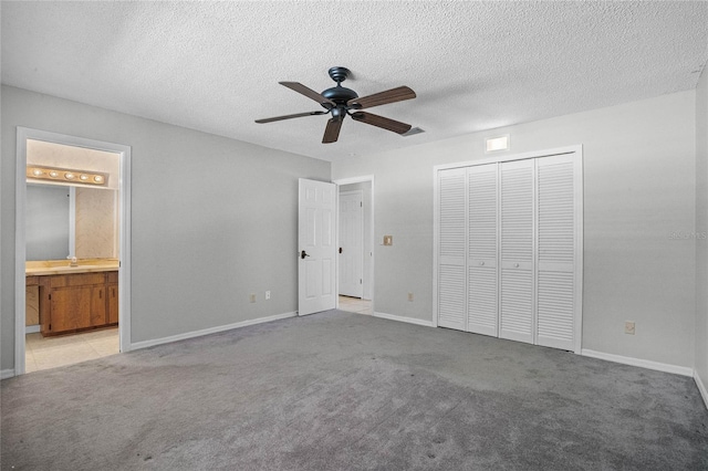 unfurnished bedroom with light colored carpet, ensuite bath, ceiling fan, and a closet