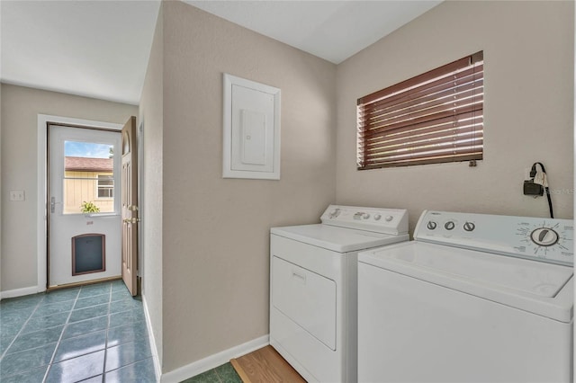 washroom featuring electric panel, dark tile patterned flooring, and washer and clothes dryer