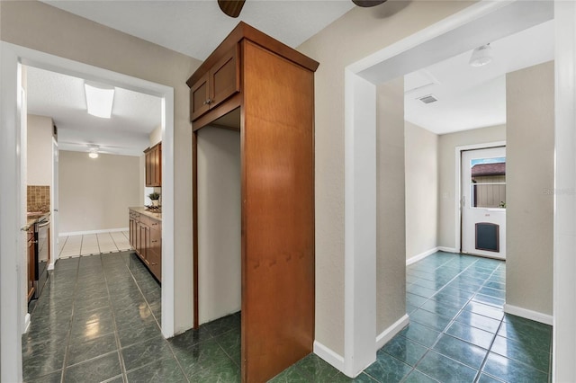 kitchen featuring ceiling fan and dark tile patterned floors