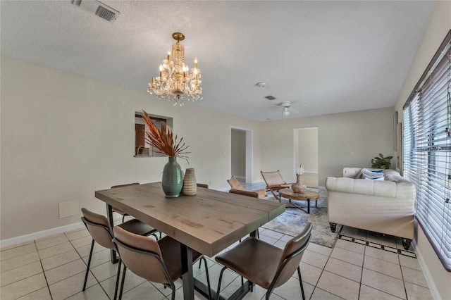 dining area with ceiling fan with notable chandelier, light tile patterned floors, and a textured ceiling