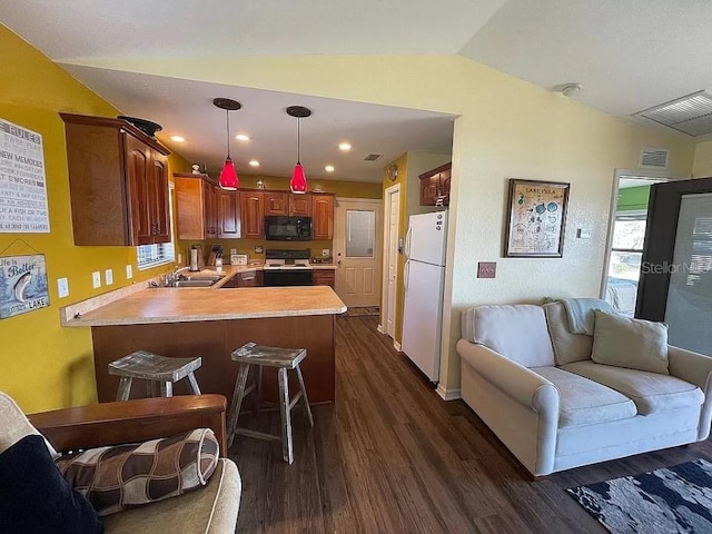 kitchen with dark hardwood / wood-style floors, kitchen peninsula, white appliances, vaulted ceiling, and sink