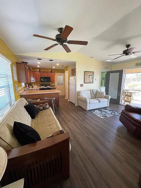 living room featuring dark wood-type flooring, ceiling fan, and vaulted ceiling