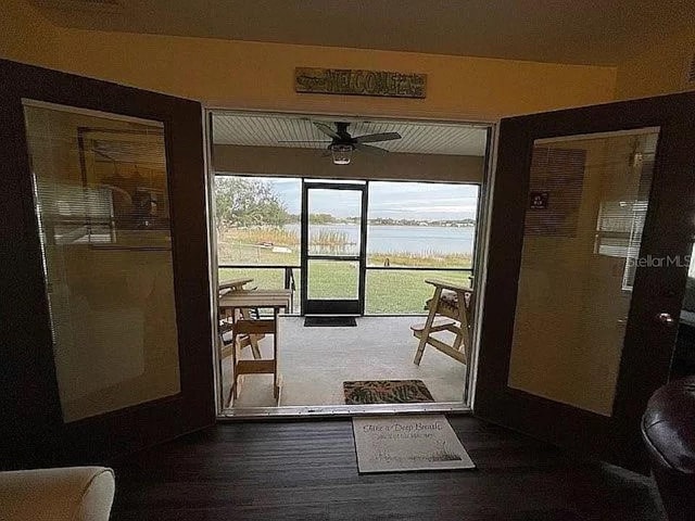 doorway to outside with ceiling fan and a water view