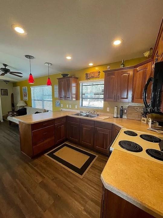 kitchen featuring stove, dark hardwood / wood-style floors, pendant lighting, tasteful backsplash, and ceiling fan