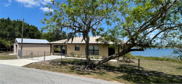 ranch-style house featuring a fenced front yard, stucco siding, driveway, and metal roof