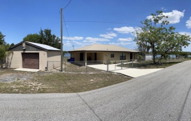 view of front of home with a detached garage, an outbuilding, driveway, and fence