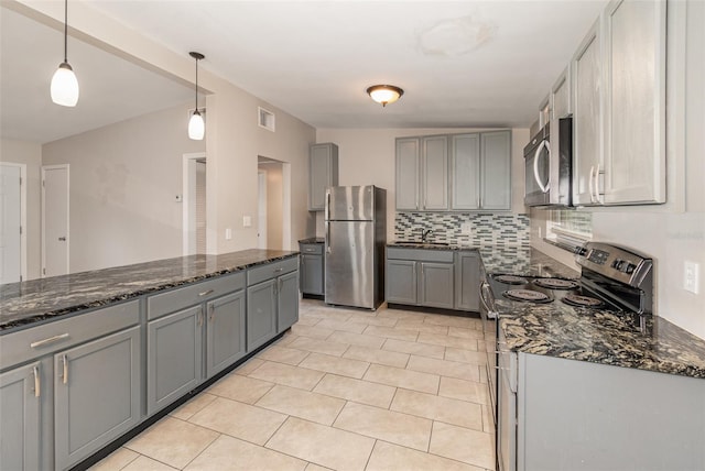 kitchen featuring dark stone counters, pendant lighting, backsplash, and stainless steel appliances