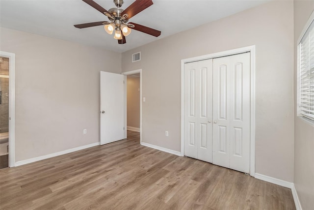 unfurnished bedroom featuring ensuite bath, a closet, ceiling fan, and light wood-type flooring