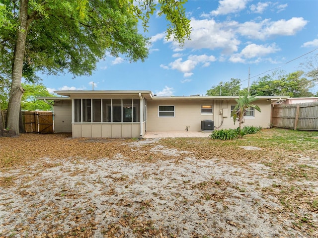 rear view of house featuring central AC unit, a sunroom, and a patio