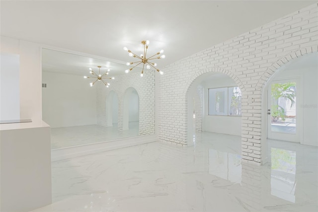 tiled empty room featuring brick wall and an inviting chandelier