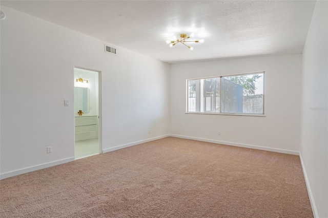 carpeted empty room with an inviting chandelier