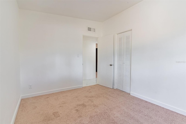 unfurnished bedroom featuring a closet and light colored carpet