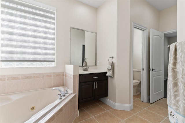 bathroom with tile patterned flooring, vanity, tiled bath, and toilet