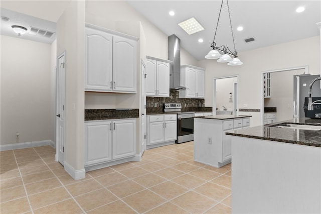 kitchen featuring wall chimney exhaust hood, pendant lighting, stainless steel appliances, and white cabinets