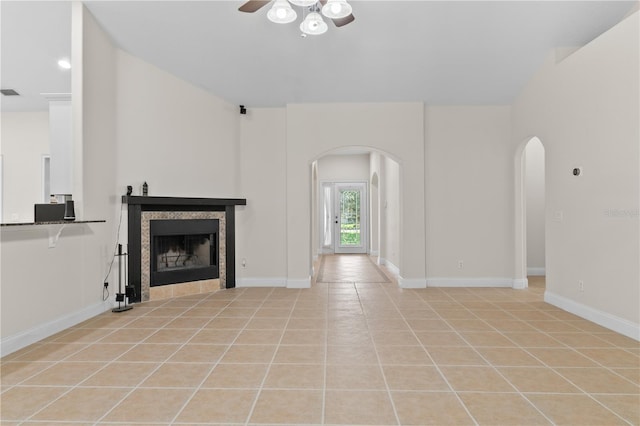 unfurnished living room with a tile fireplace, light tile patterned flooring, and ceiling fan