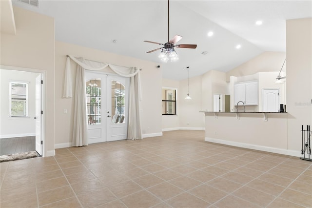 unfurnished living room with high vaulted ceiling, light tile patterned floors, ceiling fan, and french doors