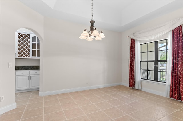 spare room featuring light tile patterned floors and an inviting chandelier