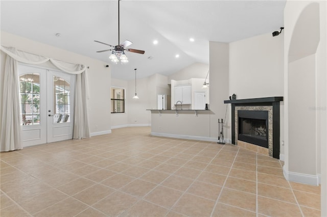 unfurnished living room featuring light tile patterned flooring, french doors, sink, vaulted ceiling, and ceiling fan