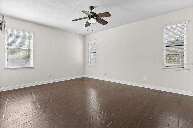 unfurnished room featuring dark wood-type flooring, a wealth of natural light, and ceiling fan