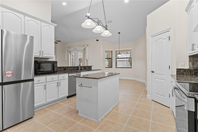 kitchen with dark stone countertops, stainless steel appliances, hanging light fixtures, and white cabinets