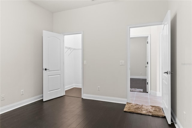 unfurnished bedroom featuring a spacious closet, dark hardwood / wood-style flooring, and a closet