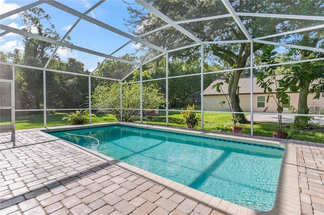 view of pool featuring a patio, glass enclosure, and a lawn