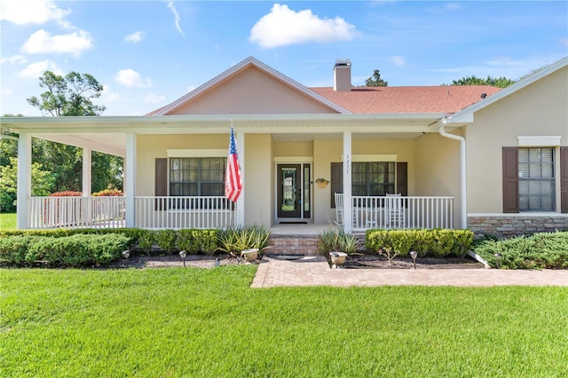 ranch-style home featuring covered porch and a front lawn