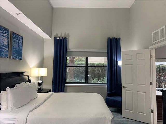 bedroom with carpet flooring, a towering ceiling, and multiple windows