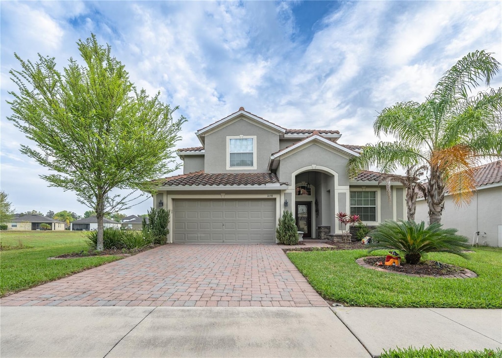 mediterranean / spanish-style home featuring a front yard and a garage