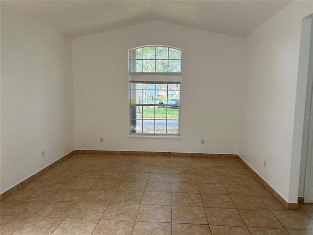 spare room featuring vaulted ceiling and light tile patterned flooring