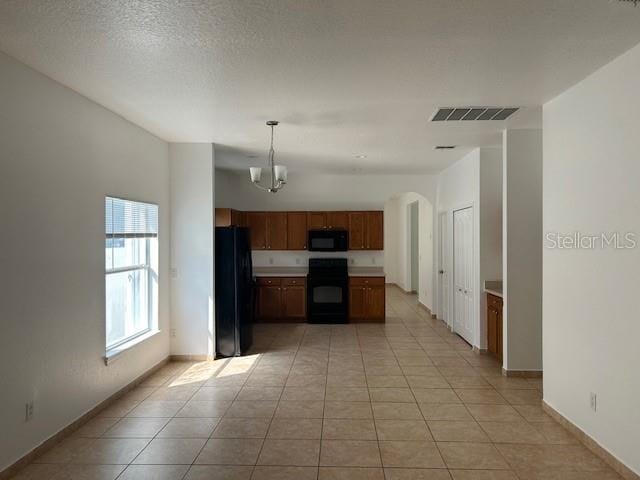 kitchen with a chandelier, a textured ceiling, light tile patterned flooring, black appliances, and decorative light fixtures