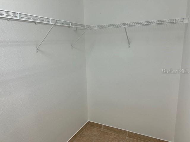 walk in closet featuring dark tile patterned floors