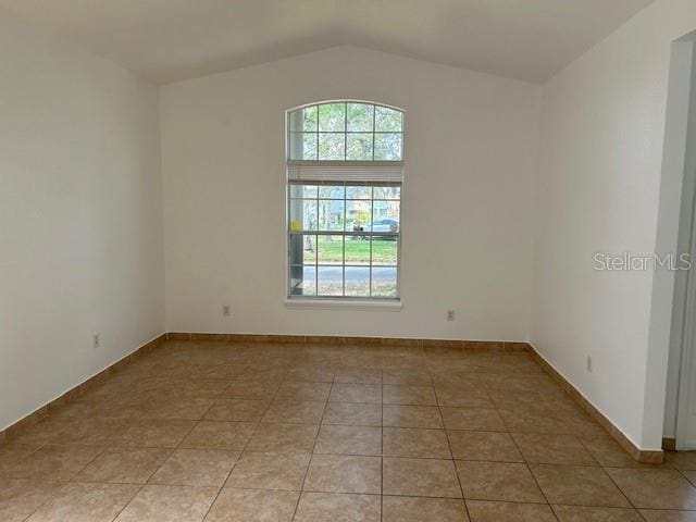 spare room with light tile patterned floors and vaulted ceiling