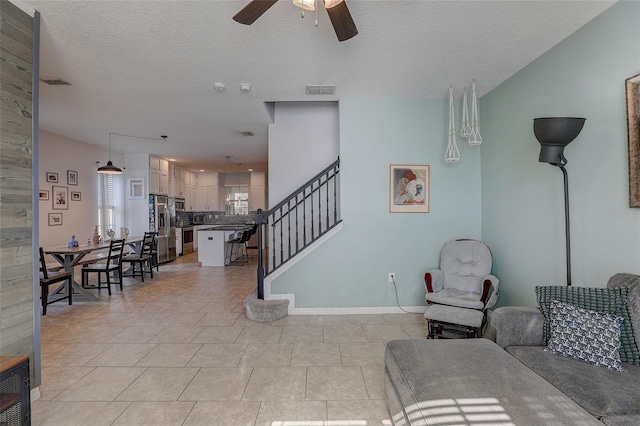 living room with light tile flooring, ceiling fan, and a textured ceiling