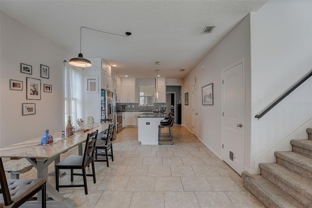 tiled dining room featuring a textured ceiling and a wealth of natural light