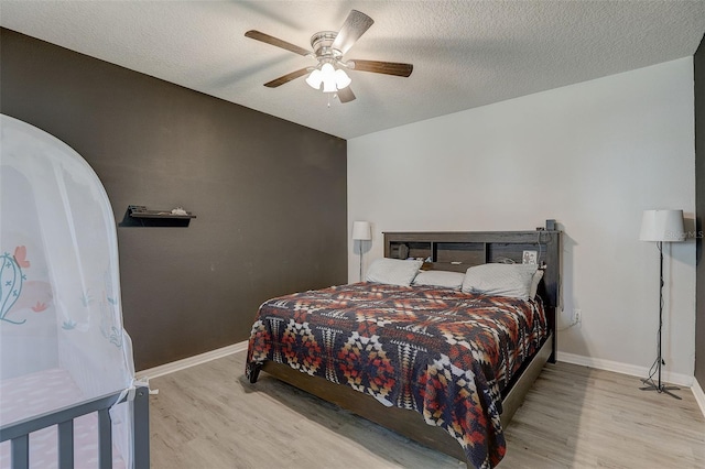 bedroom with light hardwood / wood-style floors, a textured ceiling, and ceiling fan