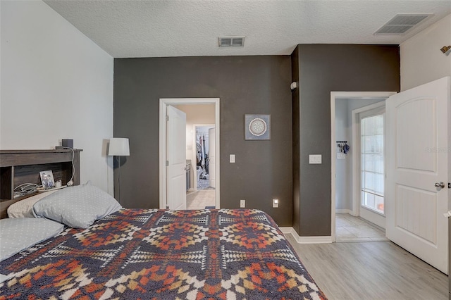 bedroom featuring light hardwood / wood-style floors, a textured ceiling, and a fireplace