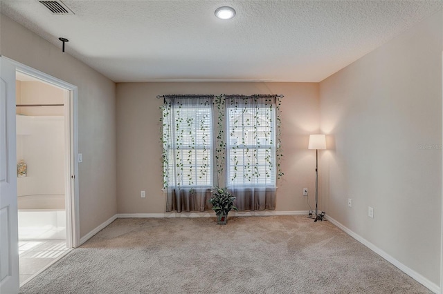 spare room with light colored carpet and a textured ceiling