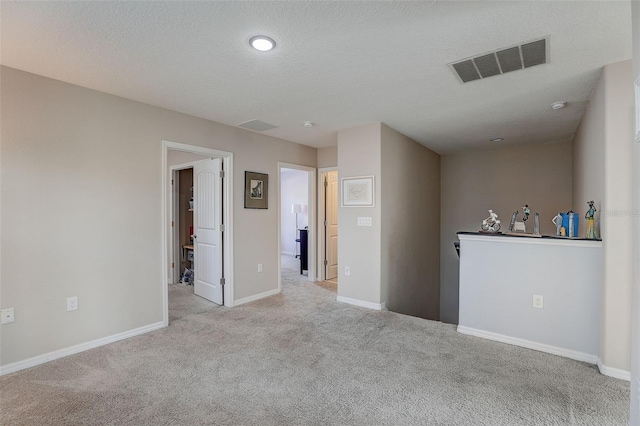 spare room featuring a textured ceiling and light colored carpet