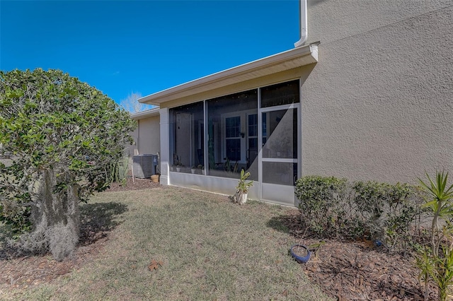 view of property exterior featuring a lawn, central air condition unit, and a sunroom